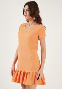 Orange short-sleeve dress with a v-neck, textured fabric, and a ruffled hem. The design is fitted at the top, flaring out at the bottom.