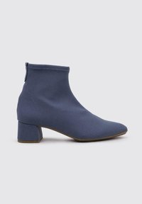 Botte de cheville en tissu texturé bleu foncé, présentant un bout pointu et un large talon carré. Fini lisse avec un ajustement serré au niveau de la cheville.