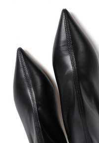 Czarne skórzane botki za kostkę z wysmukłym noskiem, z widocznymi detalami ściegów, gładką powierzchnią i elegancką sylwetką.