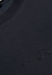 Felpa blu navy caratterizzata da un colletto rotondo, tessuto testurizzato e logo nero in rilievo sulla parte anteriore.
