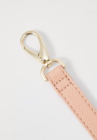 Rosa texturerad läderrem med guldfärgad metallklämma. Klämman har en fjädrande mekanism för säker fäste.