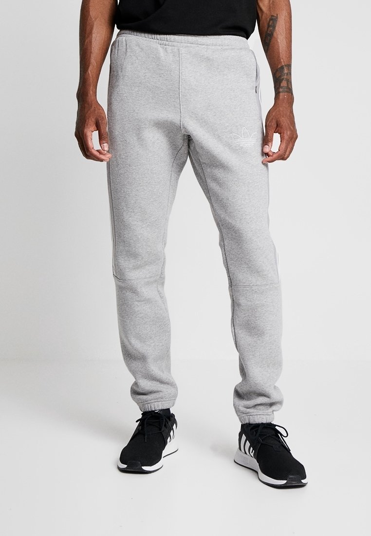 Grå träningsoverallsbyxor i mjukt, strukturerat tyg med resårlinning, sidfickor och en subtil logo på vänster lår.