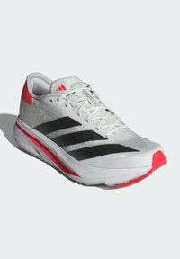 White athletic shoe with black stripes and a red accent. Features a lightweight mesh upper and a cushioned sole for performance.