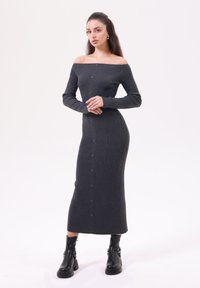 Grå ribbad stickad off-shoulder klänning med långa ärmar, knapprad fram och en figursydd silhuett, ihop med svarta ankellång stövlar.