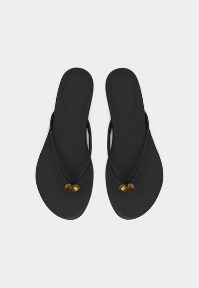 Μαύρα επίπεδα σανδάλια με λεπτά λουράκια που φέρουν μικρά διακοσμητικά σε σχήμα καρδιάς από χρυσό, σε λευκό φόντο.