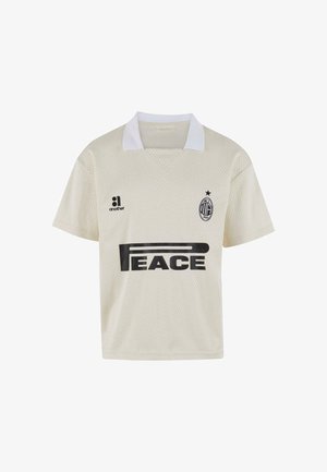 Majica za nogomet od mrežastog materijala boje krema s bijelim ovratnikom. Na lijevoj strani ima veliki crni natpis "PEACE" i logo tima. Prozračan materijal.
