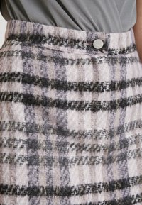 Jupe en mélange de laine à motif à carreaux rose, noir et gris. Elle présente une fermeture à boutons et un tissu texturé, conçue avec une coupe droite.