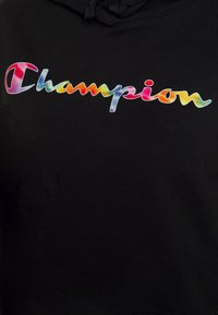 Svart hoodie med en färgglad "Champion"-logotyp i gradientnyanser, med en slät textur och en huva med dragsko.