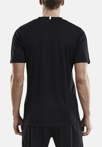 Camiseta atlética negra con mangas cortas, escote redondo y una pequeña etiqueta blanca en la parte posterior. Fabricada con una tela suave y ligera.