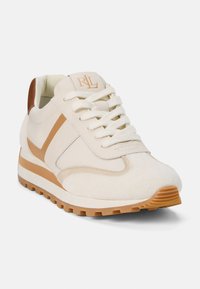 Sneaker z kremowo białą cholewką, zamszowymi detalami i brązowymi paskami. Posiada okrągłe sznurówki oraz teksturowaną gumową podeszwę dla lepszej przyczepności.