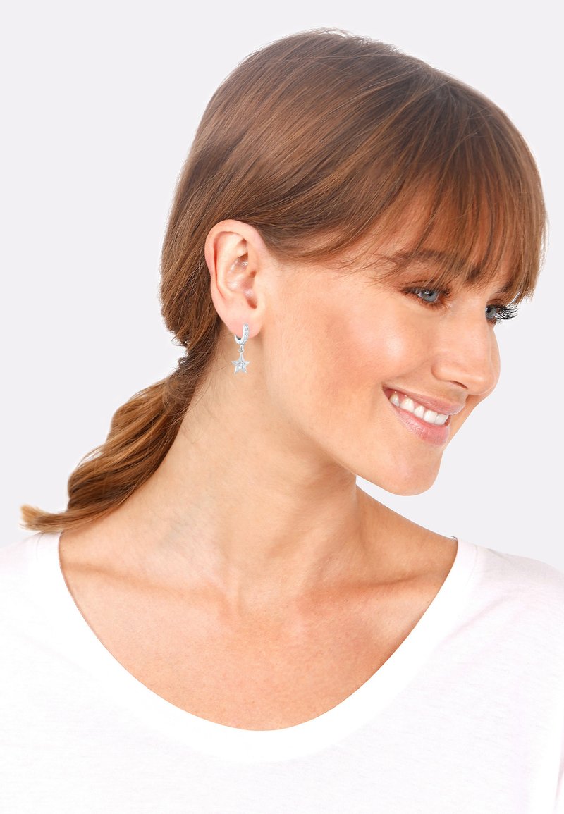 Pendientes de estrella de plata esterlina con un pequeño diseño de aro; acabado pulido y charm de estrella colgante, que muestra una superficie brillante y reflectante.