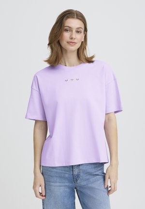 Lavendelfarbenes T-Shirt mit kurzen Ärmeln, rundem Ausschnitt und dekorativen Herz-Ausschnitten auf der Brust. Weicher Stoff, lockere Passform und gerade Saumnaht.