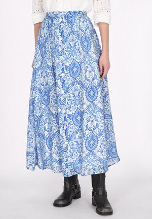 Gonna maxi con un motivo floreale blu e bianco, realizzata in tessuto leggero, con vita alta e bottoni davanti. Indossata con stivali neri.