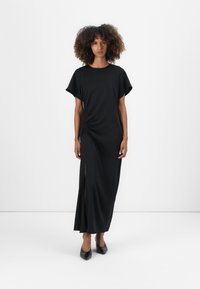 Black maxi dress with a round neckline, short sleeves, side ruching detail, and a thigh-high slit. Made from soft fabric.