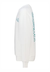 Felpa bianca in cotone con maniche lunghe, polsini a costine e un motivo turchese sul lato destro. Tessuto morbido e vestibilità rilassata.