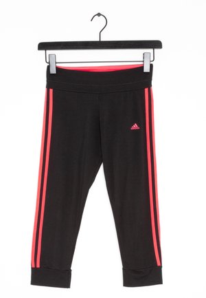 Leggings de sport noirs avec deux rayures rouges verticales de chaque côté et un logo Adidas sur la cuisse gauche. Matière douce, design ajusté.