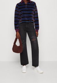 Brunrandig kort tröja med blå ränder, lila krage; svarta vida jeans med rivna detaljer; brun fluffig handväska; vita sneakers.