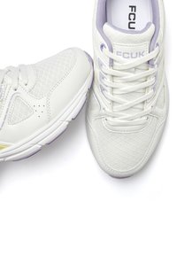 Weiße Sportschuhe mit Mesh-Einsätzen, versehen mit lila Akzenten, strukturierten Überzügen und einer Schnürung. FCUK-Logo auf der Zunge.