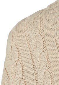 Suéter crema de punto con un diseño de cable texturizado. Hilo suave y grueso con un patrón en relieve y cuello acanalado.