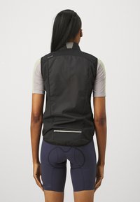 Gilet de cyclisme noir avec un design léger et respirant ; dotée d'un dos perforé, d'accents réfléchissants et d'une poche arrière.
