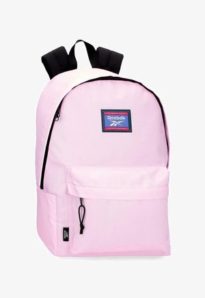 Mochila Reebok de color rosa claro con correas negras ajustables, bolsillo frontal con cremallera y parche con la marca en el panel superior delantero.