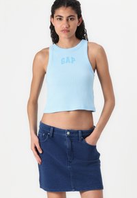 Lyseblå, ribbet tanktop med 'GAP' logo; kombinert med en mørkeblå denimskjørt med knappelukking foran og sidelommer.