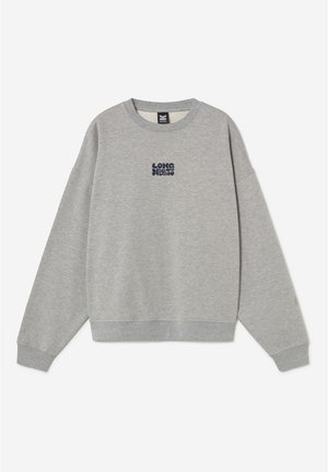 Gaiši pelēka apģērba džemperis ar apaļu kaklu un garām piedurknēm, uz krūškurvja centrā neliels teksts “LONG NIGHTS” tumšā fontā.