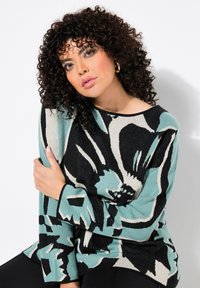 Maglione lavorato a maglia con un audace motivo floreale in nero, turchese e crema. Collo rotondo e maniche lunghe con vestibilità rilassata.