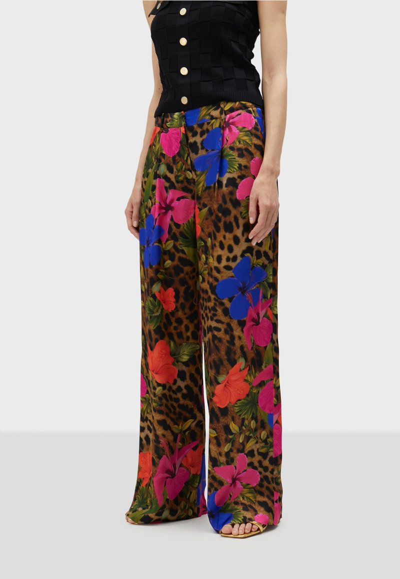 Bloemenprint pantalon met wijde pijpen en een luipaardpatroon, met levendige roze, blauwe en rode bloemen op een bruine achtergrond.