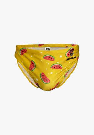 Bañador tipo slip amarillo con un patrón de rodajas de sandía en tonos rosa y verde. El material parece liso y el diseño es ajustado.