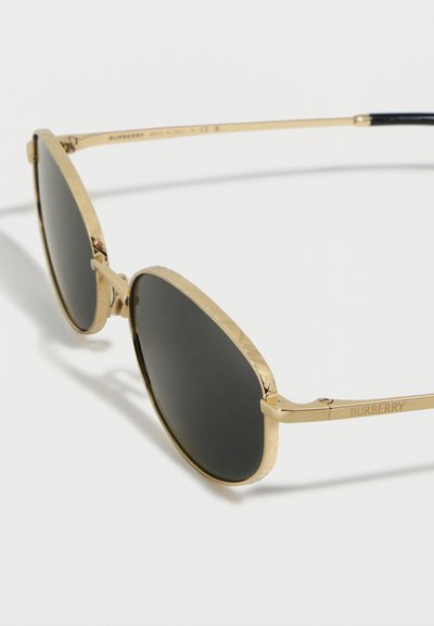 Γυαλιά ηλίου με μεταλλικό χρυσό σκελετό και μαύρους οβάλ φακούς, με χάραξη στο περίγραμμα του σκελετού και την επιγραφή "BURBERRY" στο μπράτσο του ναού.