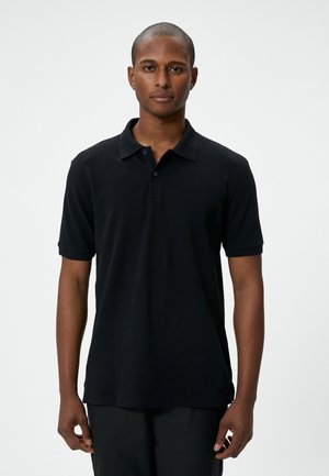 Zwarte poloshirt met een knoopsluiting en geribbelde kraag. Korte mouwen met geribbelde manchetten. Zacht katoenen materiaal, geen zichtbare patronen.