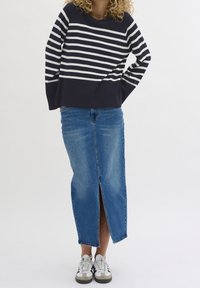 Navy and white striped sweater with long sleeves; blue denim skirt with front slit; paired with white and gray athletic shoes.