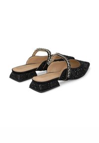 Mule nere con texture, dalla punta affusolata, con cinturino decorativo e tacco a blocco. Presentano una fodera interna liscia e decorazioni sul tacco.