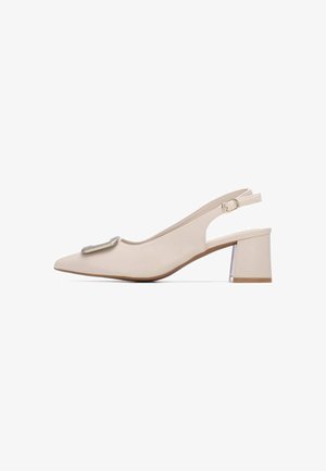 Tacones slingback beige con punta puntiaguda, que incluyen un acento metálico y un tacón grueso con base transparente. Textura de cuero suave.