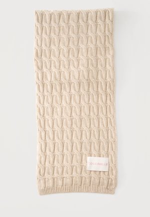 Écharpe beige tricotée avec un motif torsadé et une étiquette blanche rectangulaire portant la mention "COCCINELLE" en lettres rose clair.