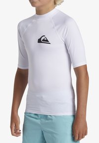 Weißes T-Shirt mit kurzen Ärmeln, gefertigt aus glattem, dehnbarem Material, mit einem schwarzen Berg-Logo auf der Brust und Flachnähten.