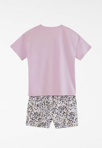 Camiseta de manga corta en color lila con cuello redondo, combinada con pantalones cortos con un fondo claro y manchas de leopardo en negro y púrpura.