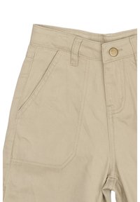Beige bomullscargobyxor med sidofickor, knappstängning och synlig texturerad sömnad vid midjan och på benen.