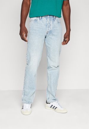 Helle blaue Denim-Jeans mit geradem Schnitt, im klassischen fünf-Taschen-Design und subtilen Ausbleichungen. Kombiniert mit weißen und schwarzen Sneakers.