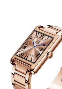 Rektangulär roséguldsur med romerska siffror, blå sekundvisare och ett polerat metallband med matt finish.