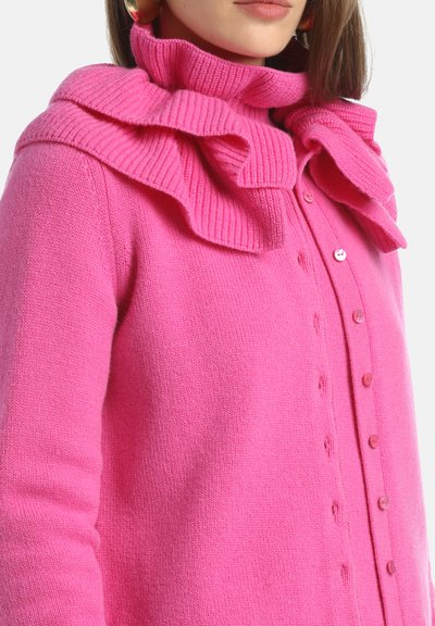 Cárdigan rosa con un cuello texturizado y con volantes, con una parte delantera abotonada y puños acanalados. Hecho de un material suave y acogedor.
