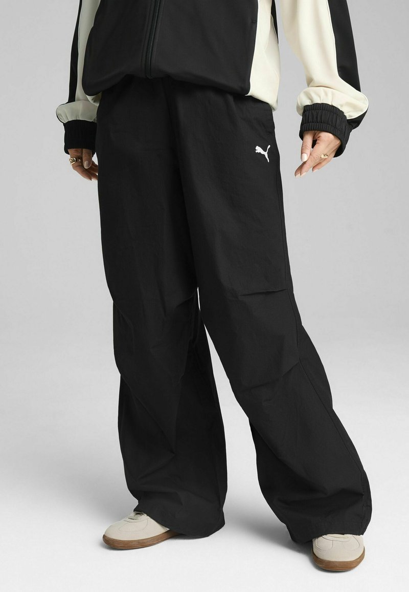 Black loose-fitting pants made of lightweight material, featuring an elastic waistband and a small white Puma logo. Accented with a smooth texture.