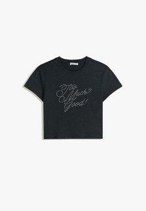 T-shirt court noir à manches courtes, avec texte en strass métalliques : « Too Much? Good! » en style cursif sur le devant.