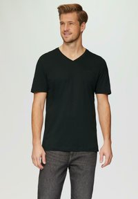 Czarny t-shirt z dekoltem w serek, wykonany z miękkiego materiału, z krótkimi rękawami, w zestawie z ciemnoszarymi dżinsami. Dopasowany krój, minimalne oznakowanie na klatce piersiowej.
