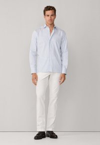 Gestreepte overhemden in lichtblauw en wit. Slim fit, lange mouwen met manchetten, gecombineerd met witte broek en zwarte schoenen.