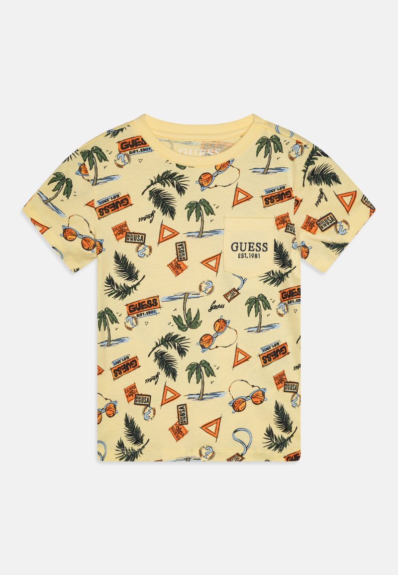 Camiseta de algodón amarilla con un estampado tropical que incluye palmeras, gafas de sol y varios elementos de marca en naranja y azul.