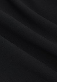 Close-up af sort stof, der viser glat tekstur og bløde folder i blødt materiale.