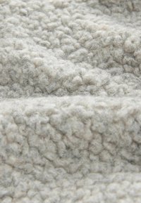 Light gray textured fabric with a fluffy, wool-like quality. The surface features a pattern of small, raised bumps. Soft and thick material.
