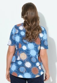 Camisa de manga corta en azul marino con un patrón abstracto y colorido de círculos de diferentes tamaños en azul claro, naranja y blanco. Hecha de tela suave.